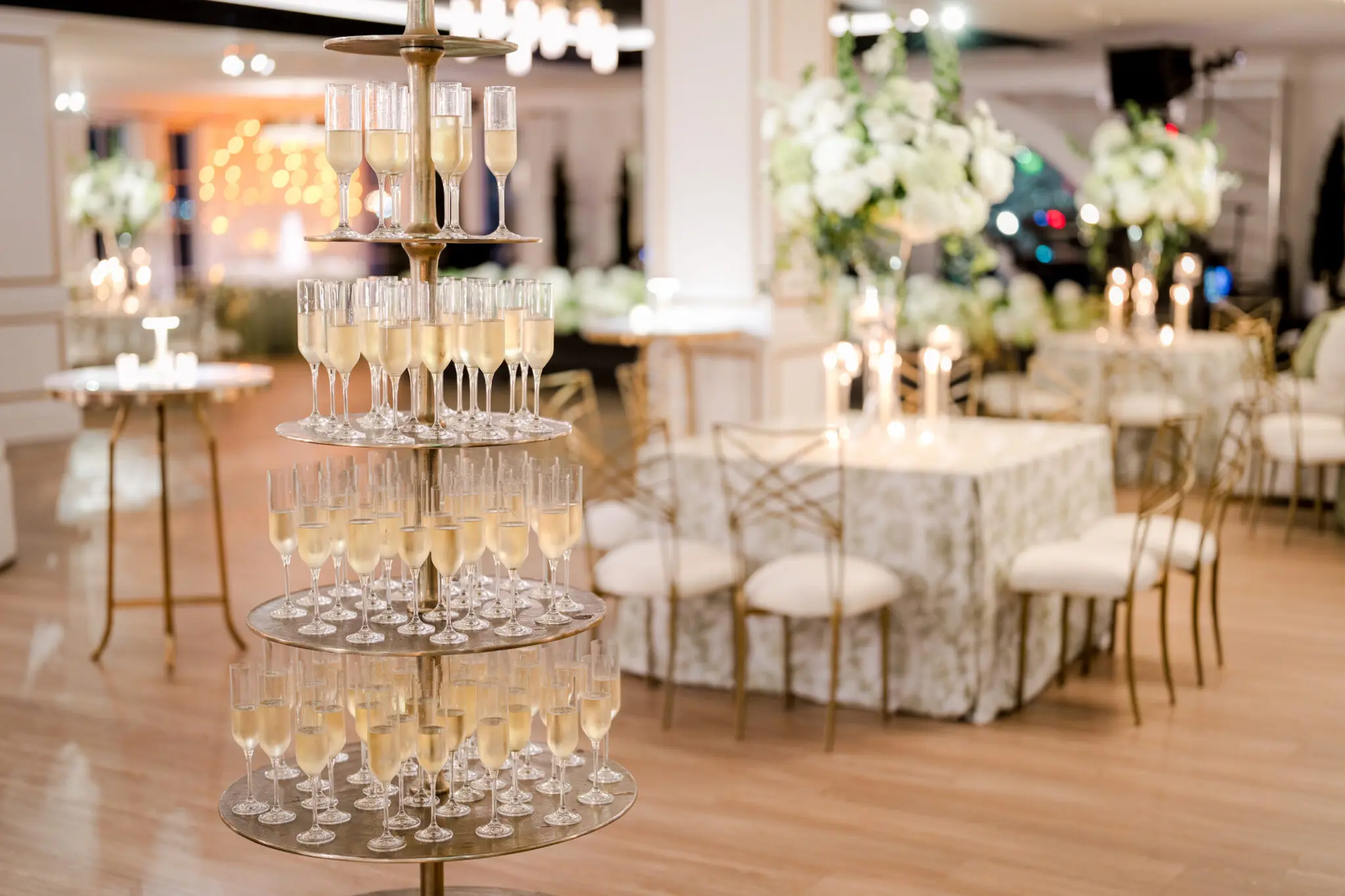 Champagne tower at The MISI by Messina’s in New Orleans wedding reception, with filled champagne flutes and floral décor in the background.