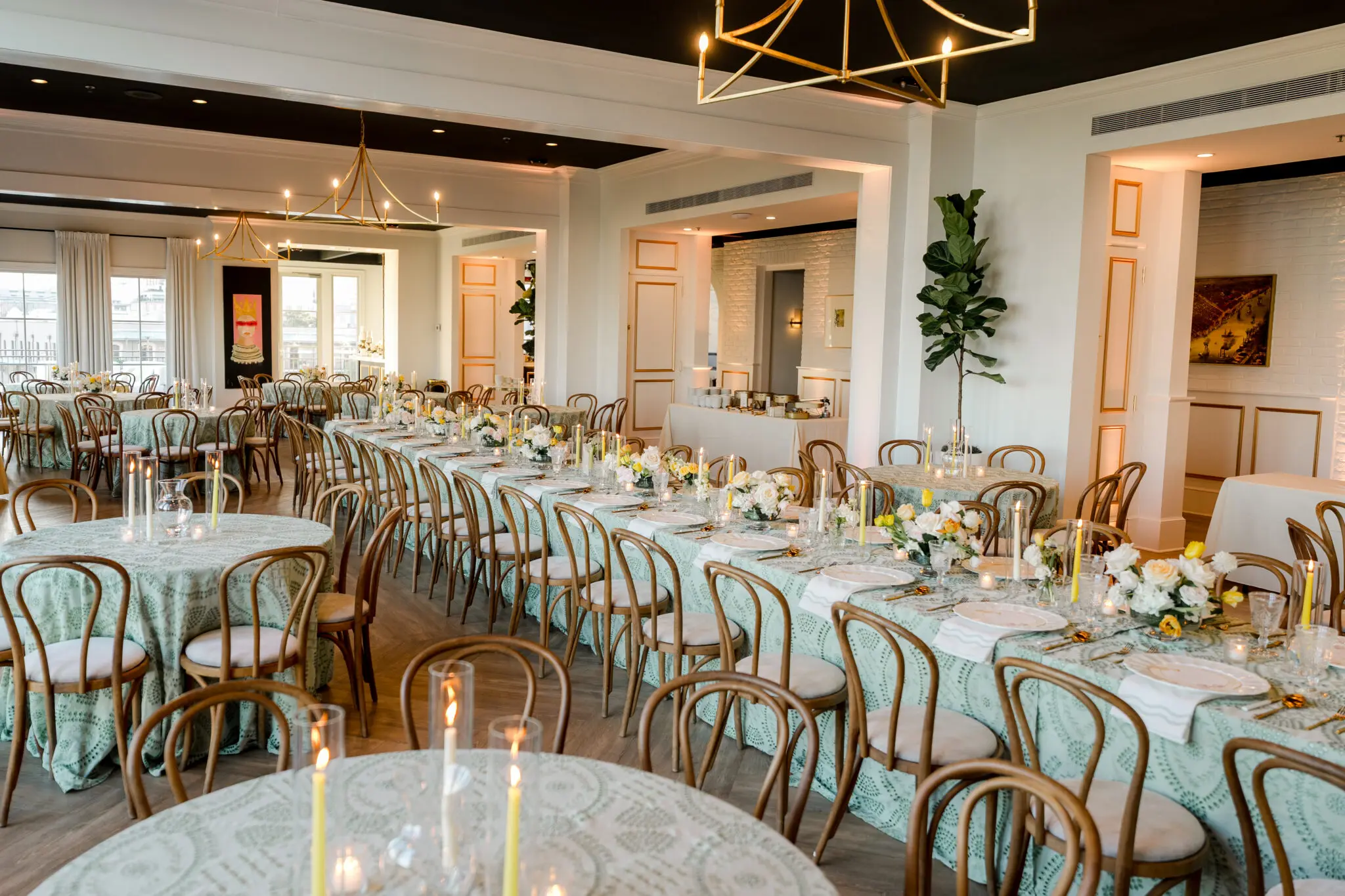 Wedding reception room at The MISI by Messina’s in New Orleans with round tables, floral centerpieces, candles, and gold-framed chairs.