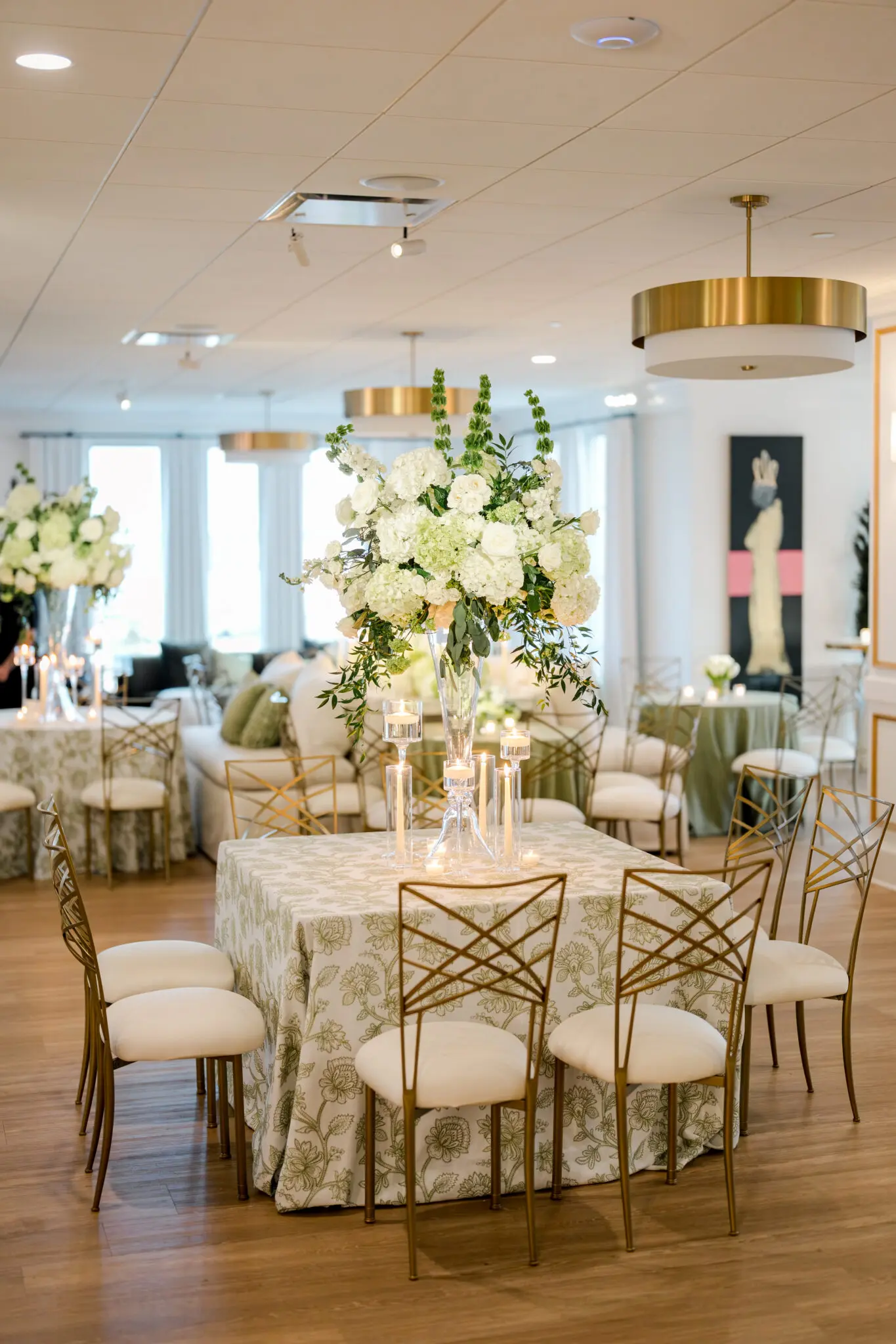 Wedding reception table décor at The MISI by Messina’s in New Orleans, featuring a large floral centerpiece, candles, patterned linens, and gold-toned chairs.