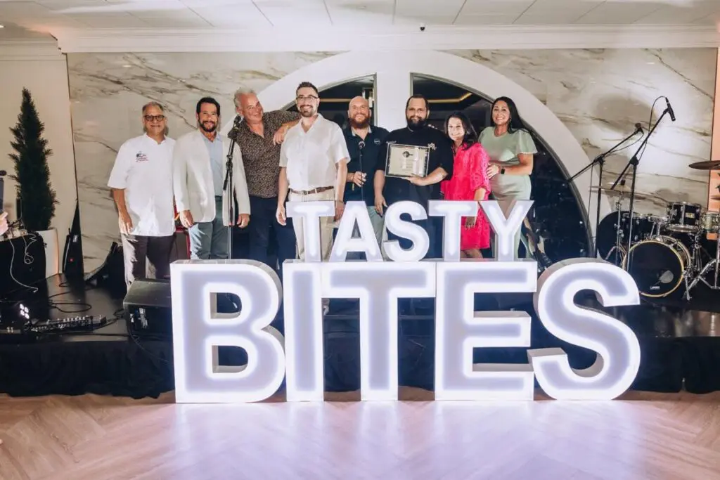 group poses onstage holding an award behind illuminated tasty bites letters at the misi in new orleans