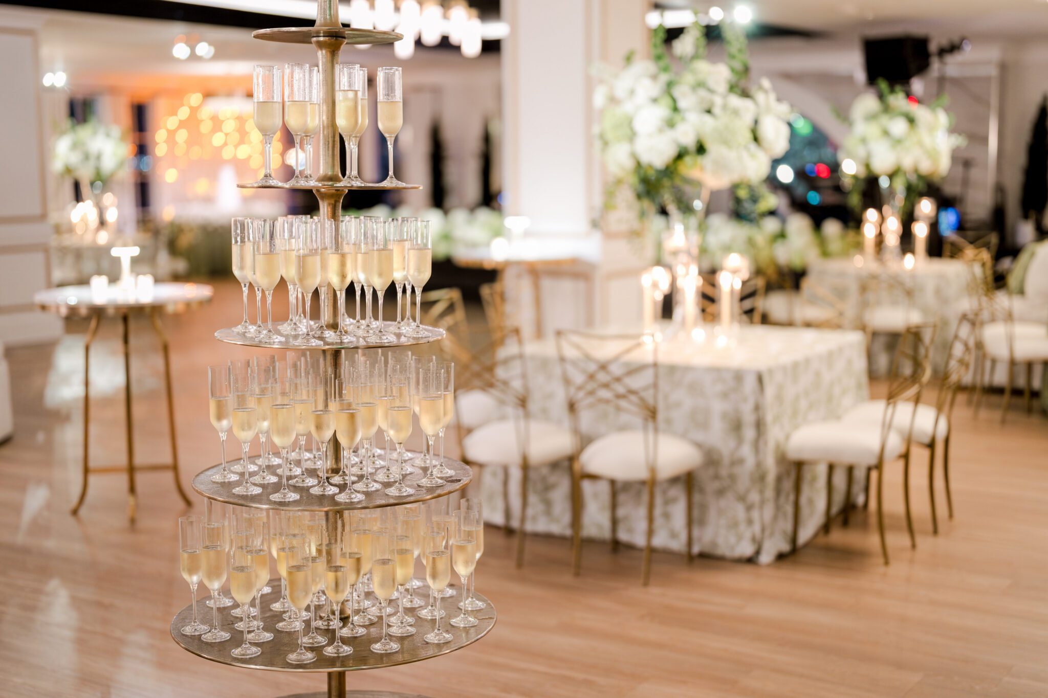 Champagne tower at The MISI by Messina’s in New Orleans wedding reception, with filled champagne flutes and floral décor in the background.