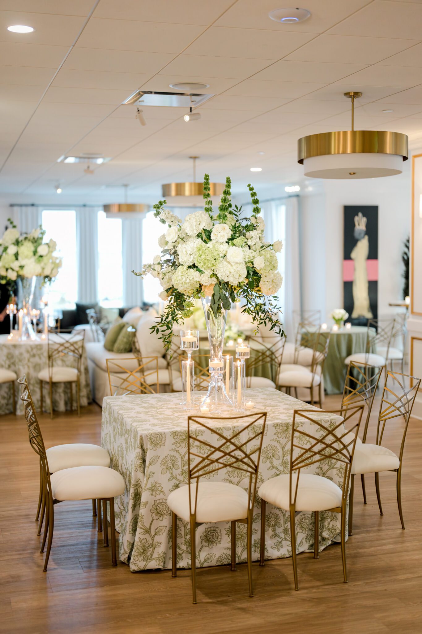 Wedding reception table décor at The MISI by Messina’s in New Orleans, featuring a large floral centerpiece, candles, patterned linens, and gold-toned chairs.