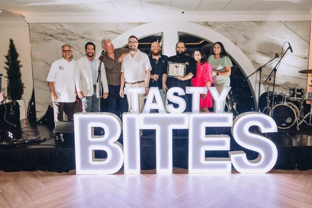 Messina’s brings home a win at tasty bites of the south 4 group poses onstage holding an award behind illuminated tasty bites letters at the misi in new orleans
